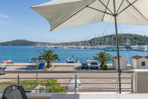 a balcony with an umbrella and a marina with boats at Seafront apartments Marija in Rogoznica