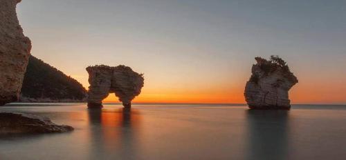 two rocks in the water with a sunset in the background at Casa Vacanze Mare Gargano in Rodi Garganico