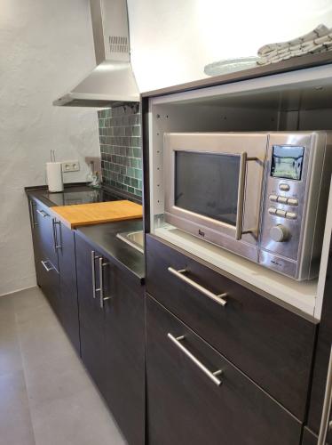 a kitchen with a microwave and a sink at La Martela de Fuentes Casa de diseño rural in Fuentes de León