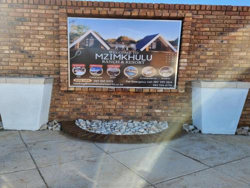 a sign on a brick wall with a fire pit at Mzimkhulu Ranch & Resort in Dinokeng Game Reserve