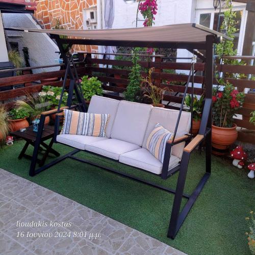 a porch swing with a white couch on a patio at Zoe garden home in Spáta