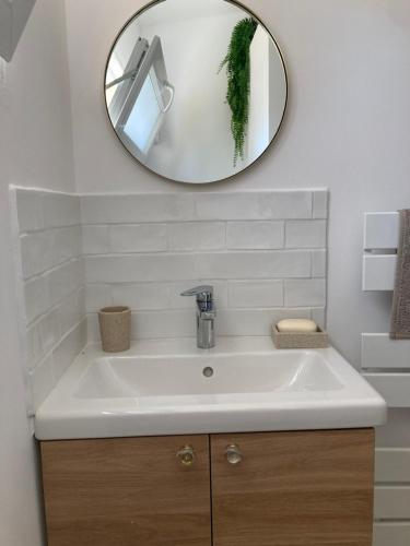 une salle de bain avec un lavabo blanc et un miroir dans l'établissement Charmante maison proche La Rochelle, à La Jarrie