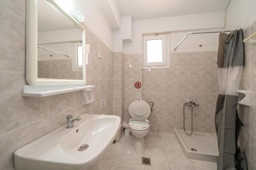 a bathroom with a sink and a toilet and a mirror at Fiore Di Mare Studios in Lassi