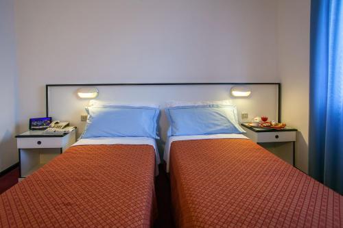 a bedroom with two beds with blue pillows at Hotel Quadrifoglio in Cagliari