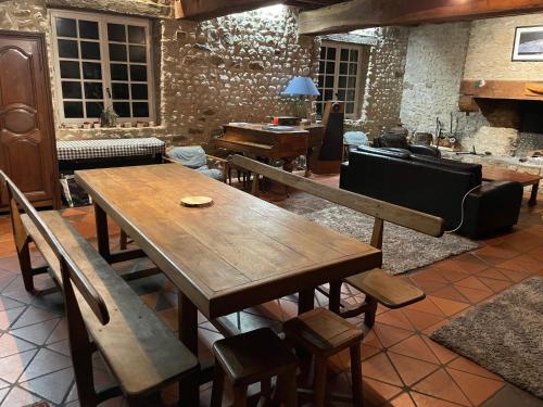 une table en bois et des bancs dans une pièce avec un piano dans l'établissement Maison de caractère, conviviale, à Boissy-le-Cutté