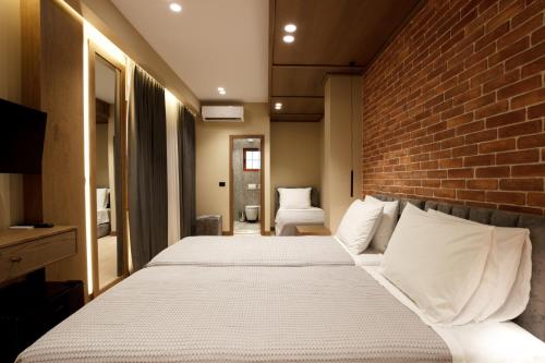 a bedroom with two beds and a brick wall at Sunny Hill Boutique Hotel in Gjirokastër