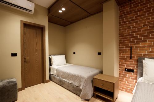 a bedroom with a bed and a brick wall at Sunny Hill Boutique Hotel in Gjirokastër