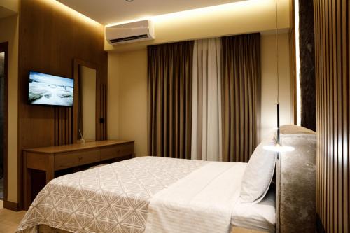 a hotel room with a bed and a flat screen tv at Sunny Hill Boutique Hotel in Gjirokastër