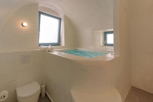a white bathroom with a tub and a toilet at Villa Karterados Suites in Karterados