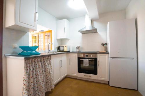 a kitchen with white cabinets and a refrigerator at House Los Angeles in Chulilla