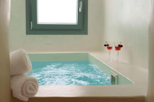 a bathroom with two glasses of red wine in a tub at Villa Karterados Suites in Karterados