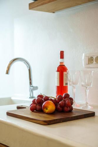a bottle of wine and a bunch of grapes on a cutting board at Villa Karterados Suites in Karterados