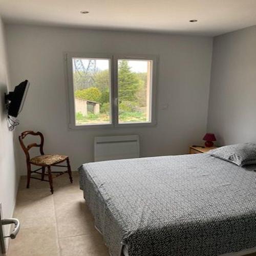 une chambre avec un lit, une chaise et une fenêtre dans l'établissement Gîte l'olivier, à Sainte-Tulle