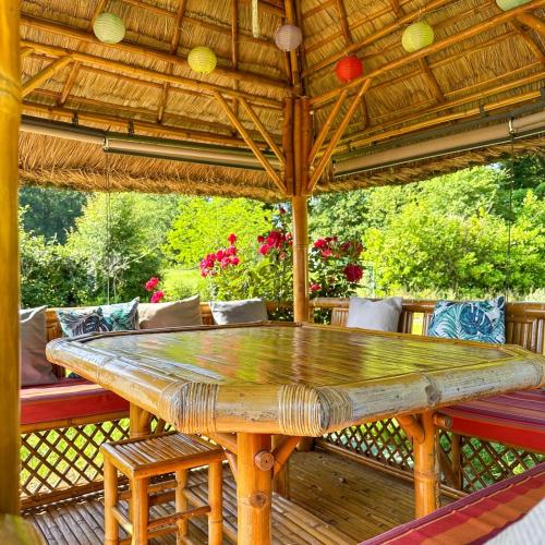 une grande table en bois sur une terrasse avec des chaises dans l'établissement Chambres à louer à la Villa l idéale, à Laubanie