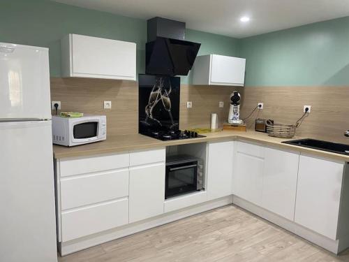 une cuisine avec des armoires blanches et un micro-ondes dans l'établissement Entre la montagne et la rivière, à Sinsat