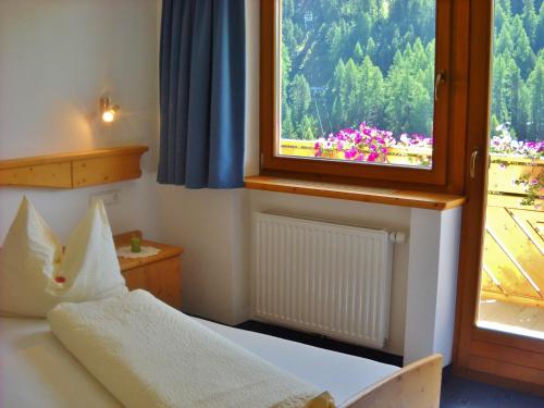 Residence Alpin في Melago: غرفة نوم بها سرير ونافذة بها زهور