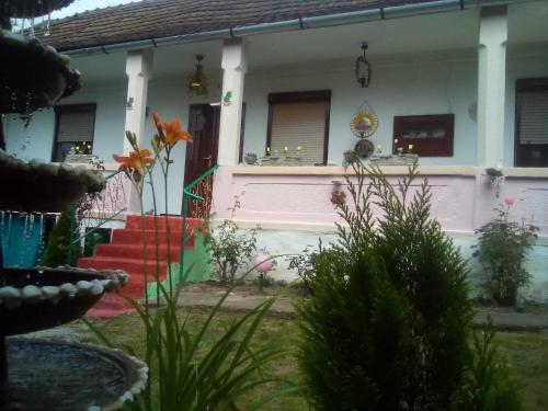 a pink and white house with some flowers in front of it at Kulcsosház vendégház in Hollóháza
