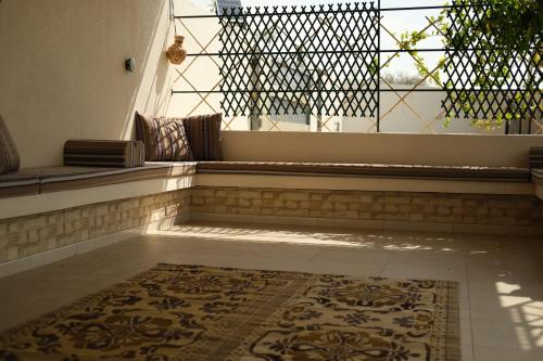 a room with a balcony with a rug on the floor at Alshuruq Stay in Al Ḩamrāʼ