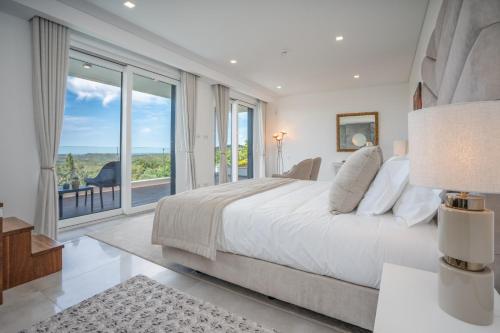 a white bedroom with a large bed and a large window at Casa da Colina in Caldas de Monchique