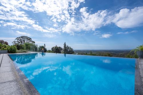 a blue swimming pool with a blue sky at Casa da Colina in Caldas de Monchique