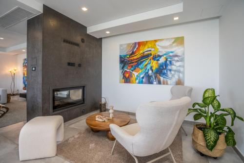 a living room with white chairs and a painting at Casa da Colina in Caldas de Monchique