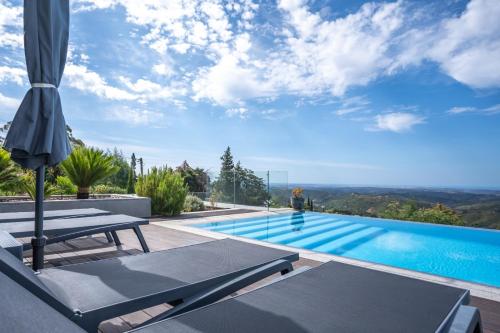 a pool with two lounge chairs and an umbrella at Casa da Colina in Caldas de Monchique