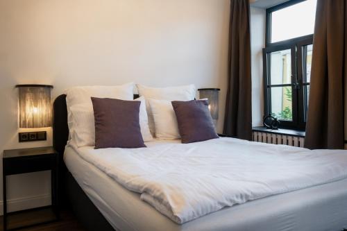 a bedroom with a bed with pillows and a window at Turgaus Self Check-in Old Town Aparthotel in Klaipėda