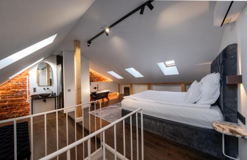 a loft bedroom with a bed and a staircase at Turgaus Self Check-in Old Town Aparthotel in Klaipėda