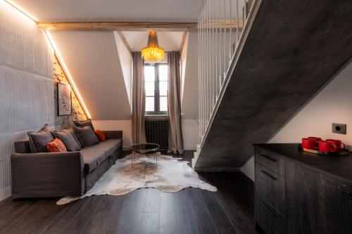 a living room with a couch and a staircase at Turgaus Self Check-in Old Town Aparthotel in Klaipėda