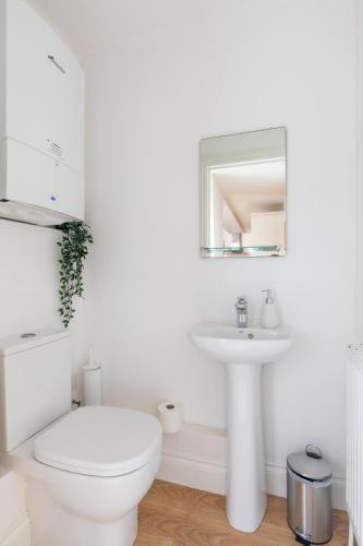 a white bathroom with a toilet and a sink at Charming Beachside Town House in Ryde
