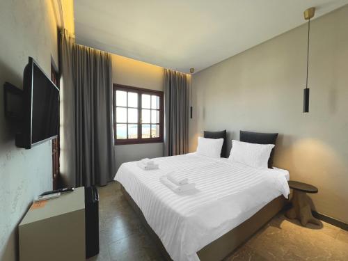 a bedroom with a white bed and a television at Viva Properties in Ouranoupoli