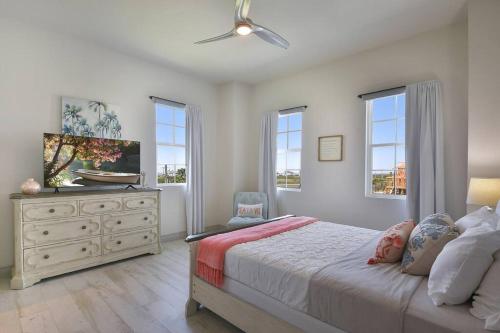 a bedroom with a bed and a dresser and windows at Rise and Shine Beach House with Ocean Views and Pointe West Resort Pools in Galveston