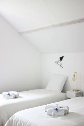 two beds in a white room with towels on them at L'Équinoxe - Parking privé - Zapart'Hôtels in Malesherbes