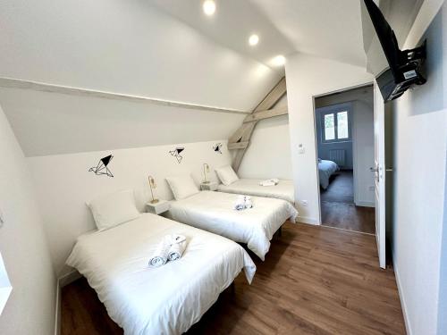 two beds in a room with white walls and wood floors at L'Équinoxe - Parking privé - Zapart'Hôtels in Malesherbes