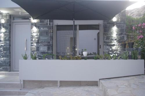 a white table with an umbrella in front of a building at Irene Luxury Apartments in Myrtos
