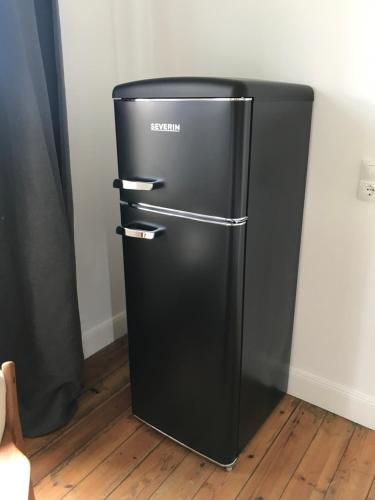 a black refrigerator in the corner of a room at Ferienwohnung in Bleckede in Bleckede
