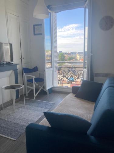 un salon avec un canapé bleu et un balcon dans l'établissement Appartement cosy vue mer, au Tréport