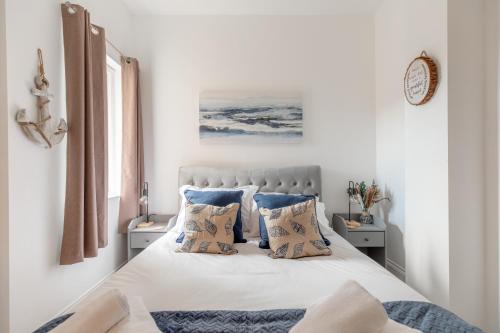 a white bedroom with a bed with blue pillows at Charming Beachside Town House in Ryde