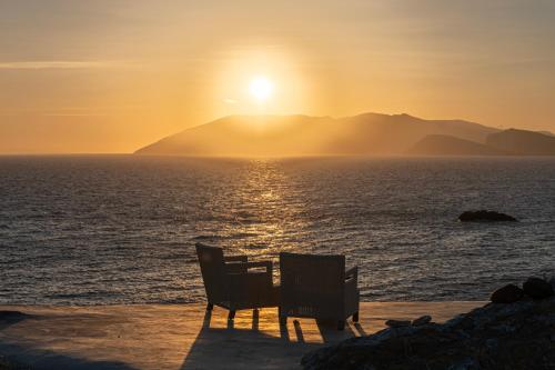a table and chairs on the beach at sunset at Onar Suites & Villas in Karavostasi