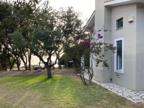 a yard with trees and a white building at Secluded seaside villa w garden sea-sunset view in Korakokhórion