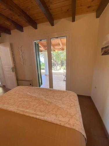 a bedroom with a bed and a sliding glass door at Secluded seaside villa w garden sea-sunset view in Korakokhórion