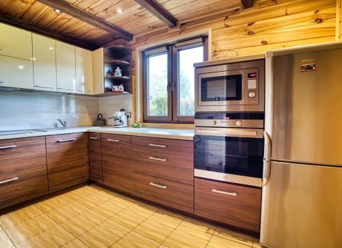 a kitchen with wooden cabinets and stainless steel appliances at Dzika Cisza DOMEK CAŁOROCZNY in Olchowiec