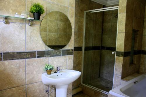 a bathroom with a sink and a shower at Honey Bee Guesthouse in Rustenburg