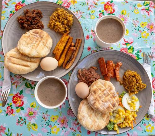 two plates of breakfast food with eggs and other foods at Adventurers Inn in Micoud