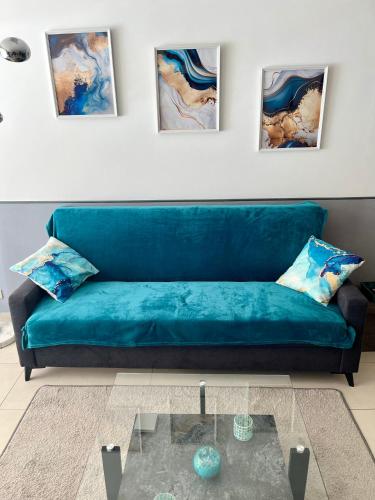 - un canapé bleu dans le salon orné de peintures murales dans l'établissement Duplex Juan les Pins proche plage, à Juan-les-Pins