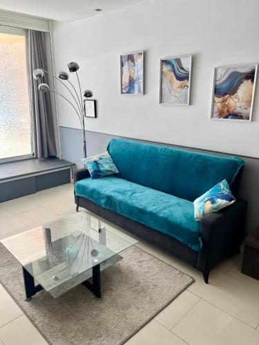 - un canapé bleu dans le salon avec une table en verre dans l'établissement Duplex Juan les Pins proche plage, à Juan-les-Pins