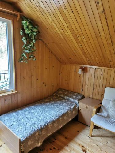 a bed in a wooden room with a chair and a window at Nina Kopalino in Kopalino