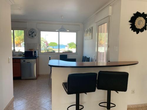 une cuisine avec un comptoir et deux tabourets de bar dans l'établissement Villa climatisée de l'Etang de THAU avec piscine, à Sète