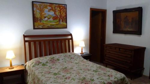a bedroom with a bed and two lamps and a painting at Casa SERRA DA BALANÇA - PÉROLA DA MANTIQUEIRA in Gonçalves