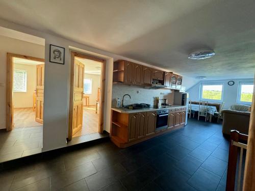 a kitchen with wooden cabinets and a living room at Chalupa Vlasta in Kadov